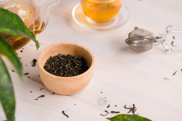 Dry tea in bowl, on wooden background