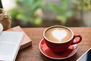 Red cup of coffee with latte art heart shape,soft focus design for valentine background