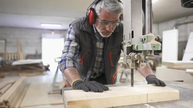 Wood worker cutting piece of wood with machine