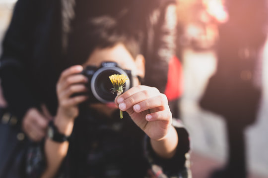 Young boy with mother taking photos of yellow flower in Cinematic color
