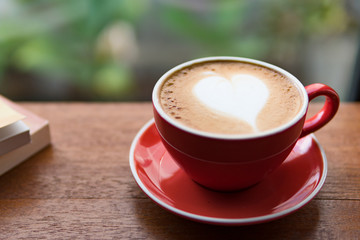 Red cup of coffee with latte art heart shape,soft focus design for valentine background