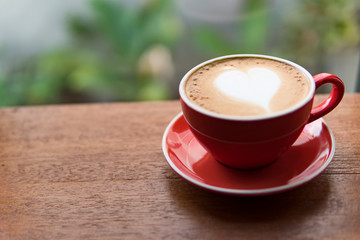 Red cup of coffee with latte art heart shape,soft focus design for valentine background
