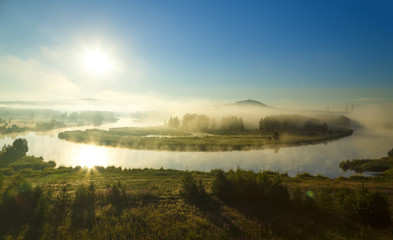 Beautiful sunrise flight sun over misty river foggy morning . Summer fog and sun on peaceful river. Holiday destination, place for rest, meditative state