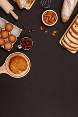 Homemade breads or bun, croissant and bakery ingredients, flour, almond nuts, hazelnuts, eggs on dark background, Bakery background frame, Cooking breakfast concept. Flat lay, Top view and copy space.