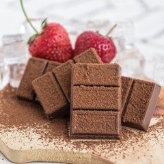 Chocolate with fresh berries on wooden table