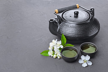 Obraz na płótnie Canvas Asian black traditional teapot and teacups with green tea for ceremony