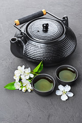 Obraz na płótnie Canvas Asian black traditional teapot and teacups with green tea for ceremony