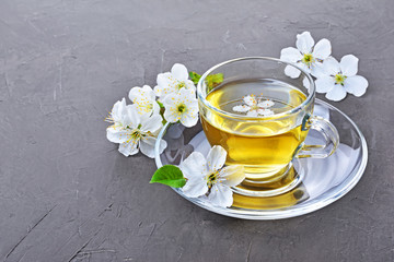 Close-up glass teacup with green tea and spring flowers