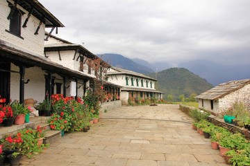 Fototapeta na wymiar Traditional architecture in Ghandruk, Annapurna Conservation Area, Nepal. Flowers in front of a row old houses.