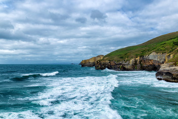 High sandy cliff and waves of Pacific ocean at Tunnel beach, New Zealand