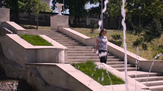 Young woman descends stone stairs in a sity parck