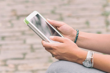 Detail of a woman using tablet in the park.