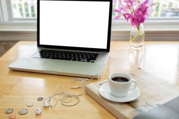 Cup of coffee on wooden desk with laptop computer