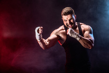 Sport concept. Sportsman muay thai boxer fighting on black background with smoke. Copy Space.