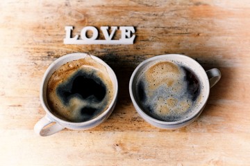 Two cups of coffee and love inscription on the wooden table