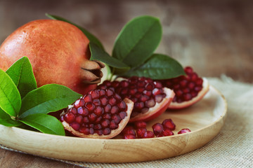Sweet and juicy Indian red pomegranate on wooden plate on wood table with copy space for background...