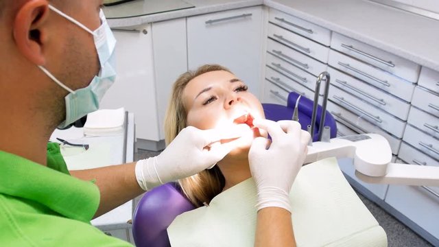 4k footage of beautiful blonde woman sitting in dentist chair and opens mouth for teeth inspection