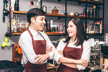 Portrait of couple barista working and standing behind the counter bar in a cafe