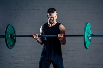 a young man doing exercises with a heavy barbell in the gym