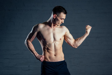 Fototapeta premium sexy naked man without clothes demonstrates the abs muscles on a dark background