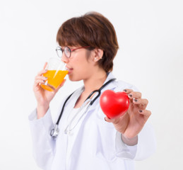 Happy woman doctor holding the red heart and orange juice.  Isolated on white background. Studio lighting. Concept for healthy and medical
