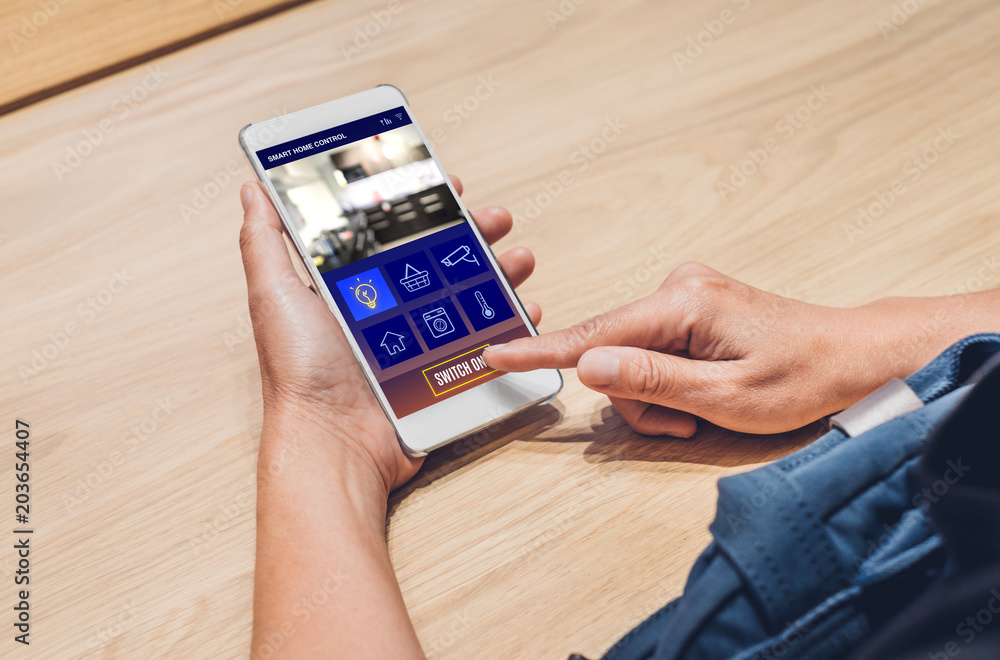 Poster Close up hand use smart home control app on mobile phone switch on light.Automation digital technology.