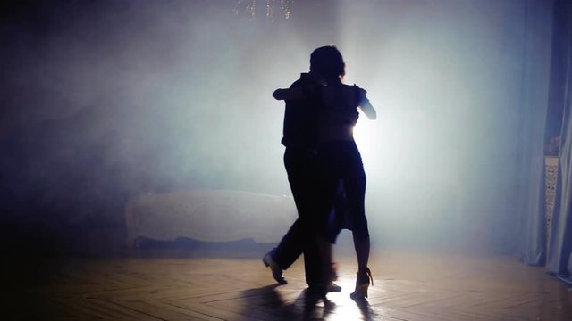 silhouette of a couple in the fog of dancing tango