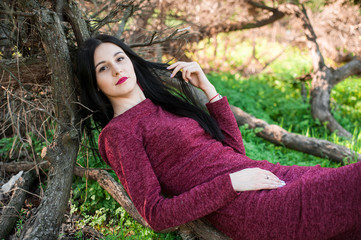 beautiful young brunette with long hair in a park on a spring in the middle of flowering trees in a...