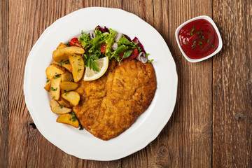 Chicken schnitzel, served with roasted potatoes and salad.