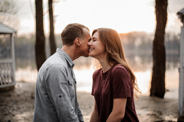 Naklejka premium Couple in love standing face to face and laughing on the background of lake