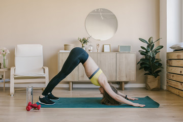 Young attractive fit woman practicing yoga and do exercises, Half Lotus pose, working out, wearing white t-shirt, pants, meditation session at floor. Full length