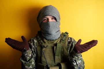 man in camouflage and mask on a yellow background. the concept of anonymity , terrorism and masked...