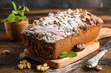 Sweet fruitcake with walnuts, dates and icing sugar on the wooden rustic table
