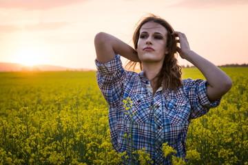 Happy young woman in a field of canola seed in bloom. Freedom, nature, ecology and happiness concept.