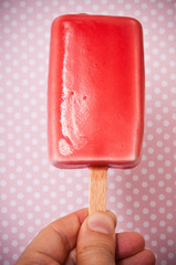 red ice cream in the form of ice lolly, woman keeping ice cream ice lolly