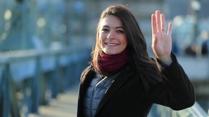 Portrait of happy young 30 year old woman waving goodbye to camera