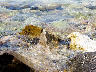 Splashes from the waves bumping against the rocky shore, The sea is dark blue with white spray