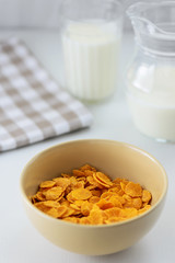 corn flakes with milk in a plate on a white table
