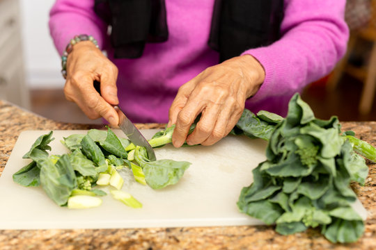 Senior Woman Cutting Kale On Chopping Board