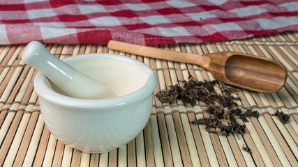 Mortar and dried herbs on bamboo mat