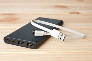 Powerbank new, powerful dark color with two usb inputs on a wooden background