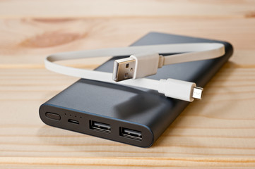 Powerbank new, powerful dark color with two usb inputs on a wooden background