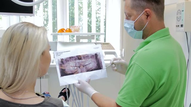 4k footage of dentist explaining teeth treatment and showing x-ray image to his patient