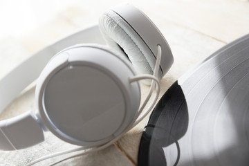 Headphones and vinyl disc on a white wooden table. Empty copy space for Editor's text.
