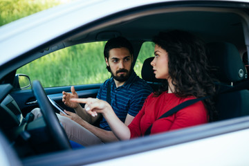 Obraz premium Driving school or test. Beautiful young woman learning how to drive car together with her instructor.