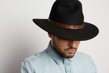 Portrait of a pensive caucasian man in hat wearing denim shirt and looking down isolated on white background