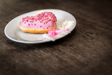pink donut with icing lies on a white plate
