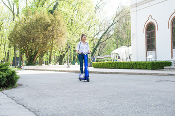 Woman using electric scooter in the park on a sunny day