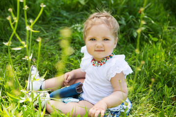 Portrait  little baby girl sits on green grass