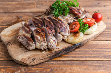 Grilled turkey fillet with spices, herbs and cherry tomatoes on a cutting board.